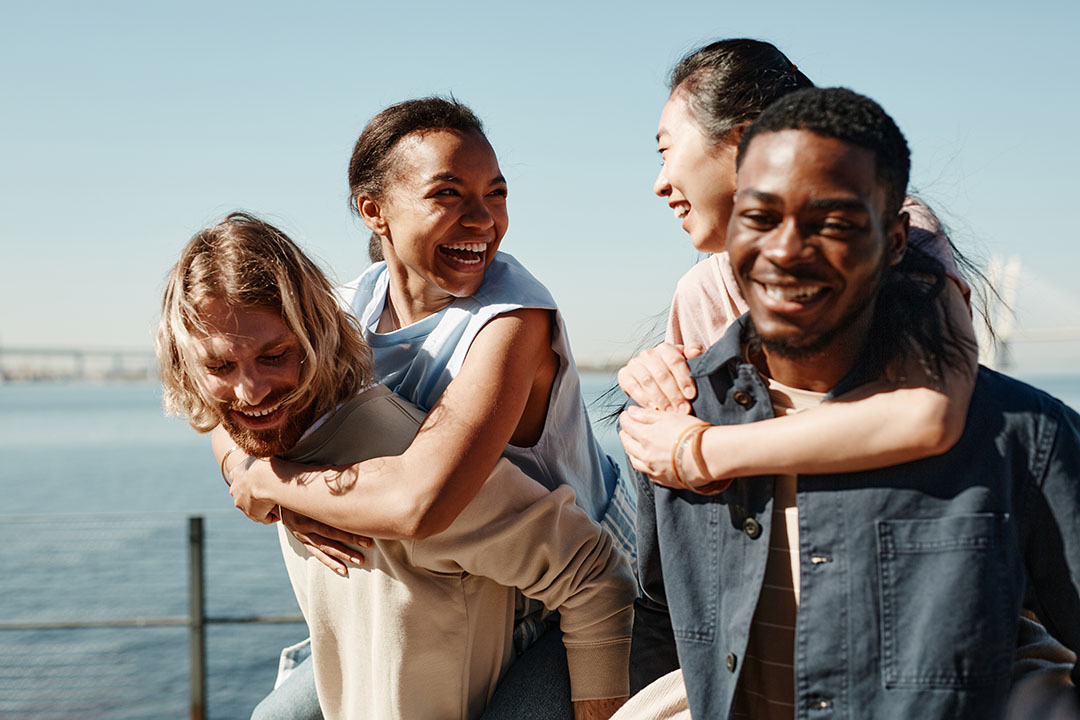 Group of adults smiling together outdoors, representing emotional wellness and healthy relationships